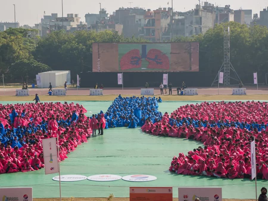 Students in coloured overalls forming the human lung image at Thyagraj Stadium.